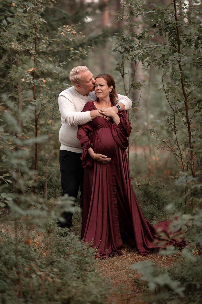 Mysig kärleksfull bild i skogen under parets gravidfotograferingen.