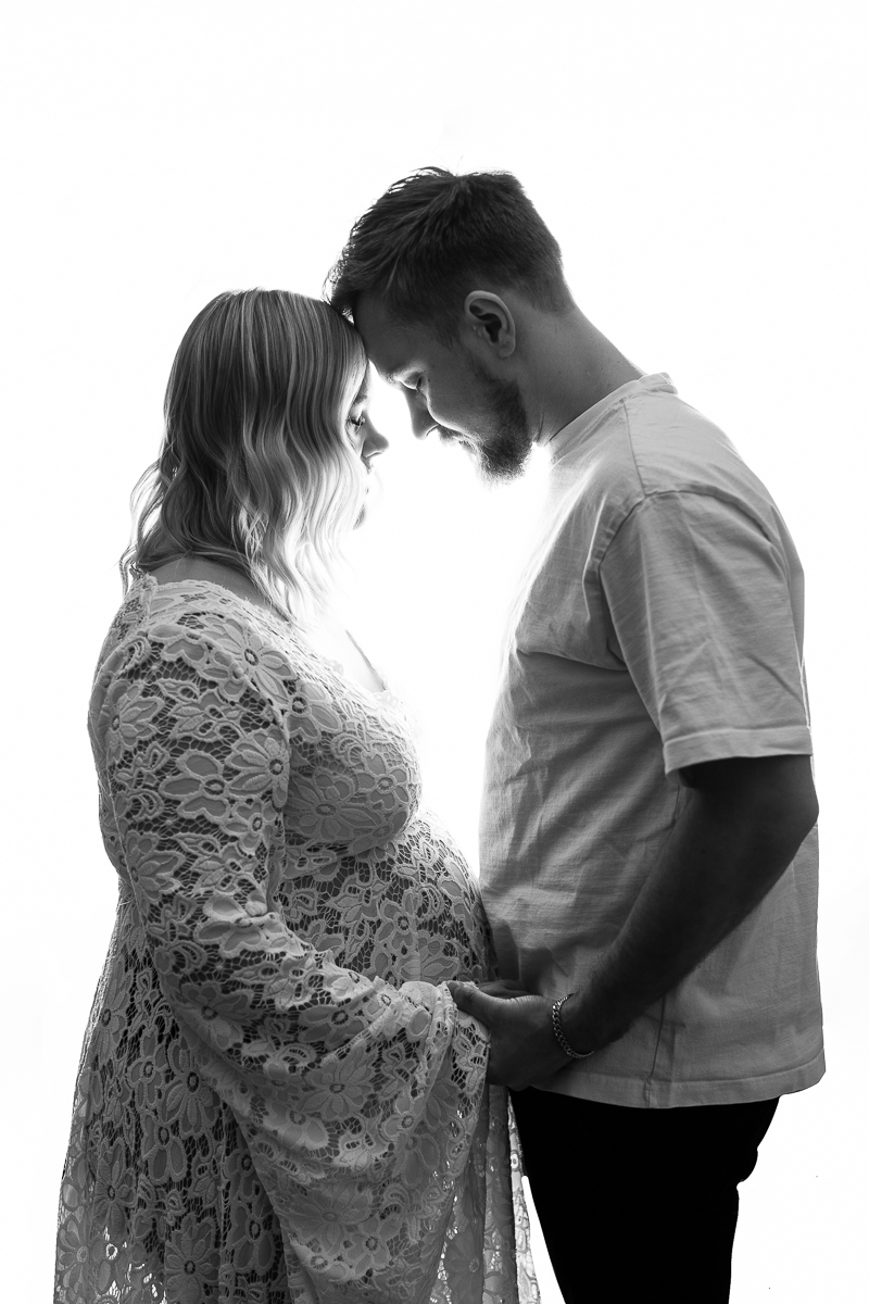 Svartvit gravidbild i studiomotljus, panna mot panna för att förstärka bandet mellan partner.